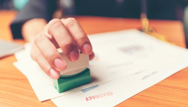Hand stamping a document as approved, representing independent validation of a law firm