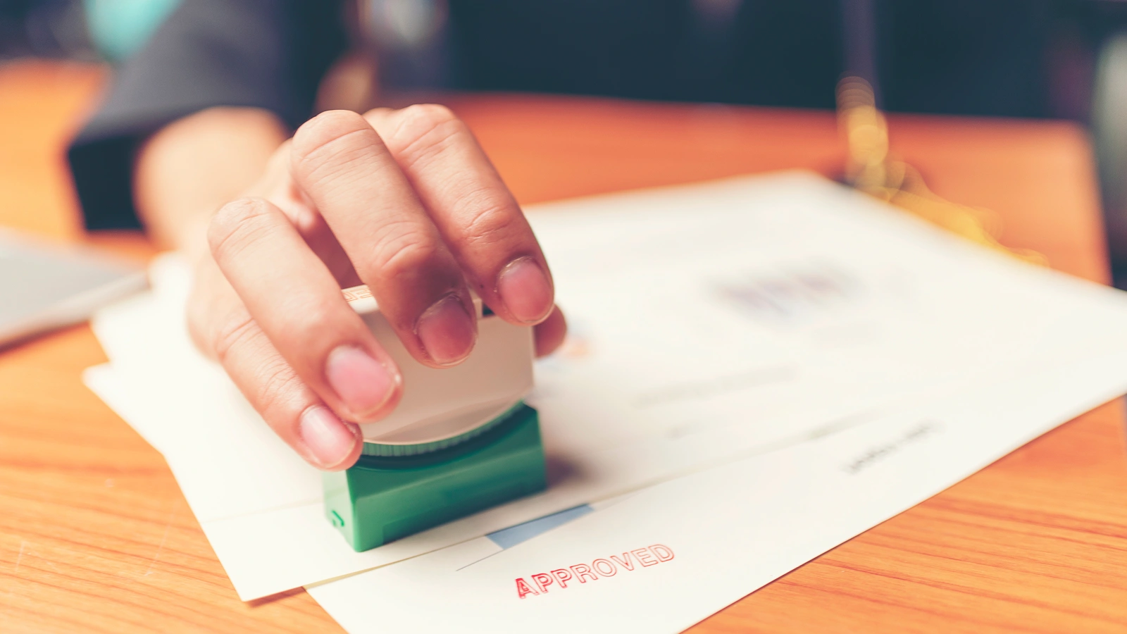 Hand stamping a document as approved, representing independent validation of a law firm